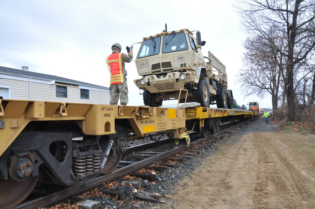 Soldier guides military vehicle on to train car