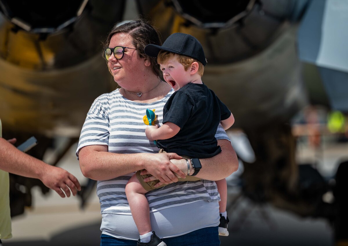 A mother and a son stand in awe as a C-47 Skytrain starts its engines before performing during the 2022 Thunder Over Dover Airshow at Dover Air Force Base, Delaware, May 22, 2022. The theme for the airshow, “Reunite,” celebrates the military and the Dover community reuniting for the first time since the COVID-19 pandemic. (U.S. Air Force photo by Senior Airman Faith Schaefer)