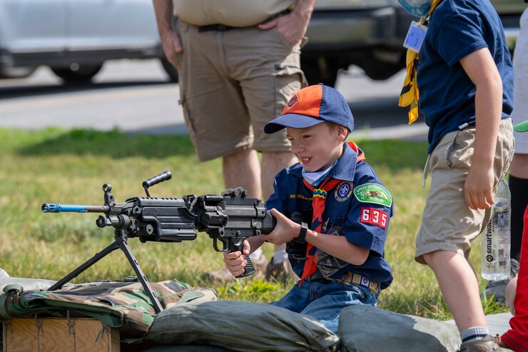 Photo of a cub scout mimic using a weapon during a group tour at the Vermont Air National Guard Base.