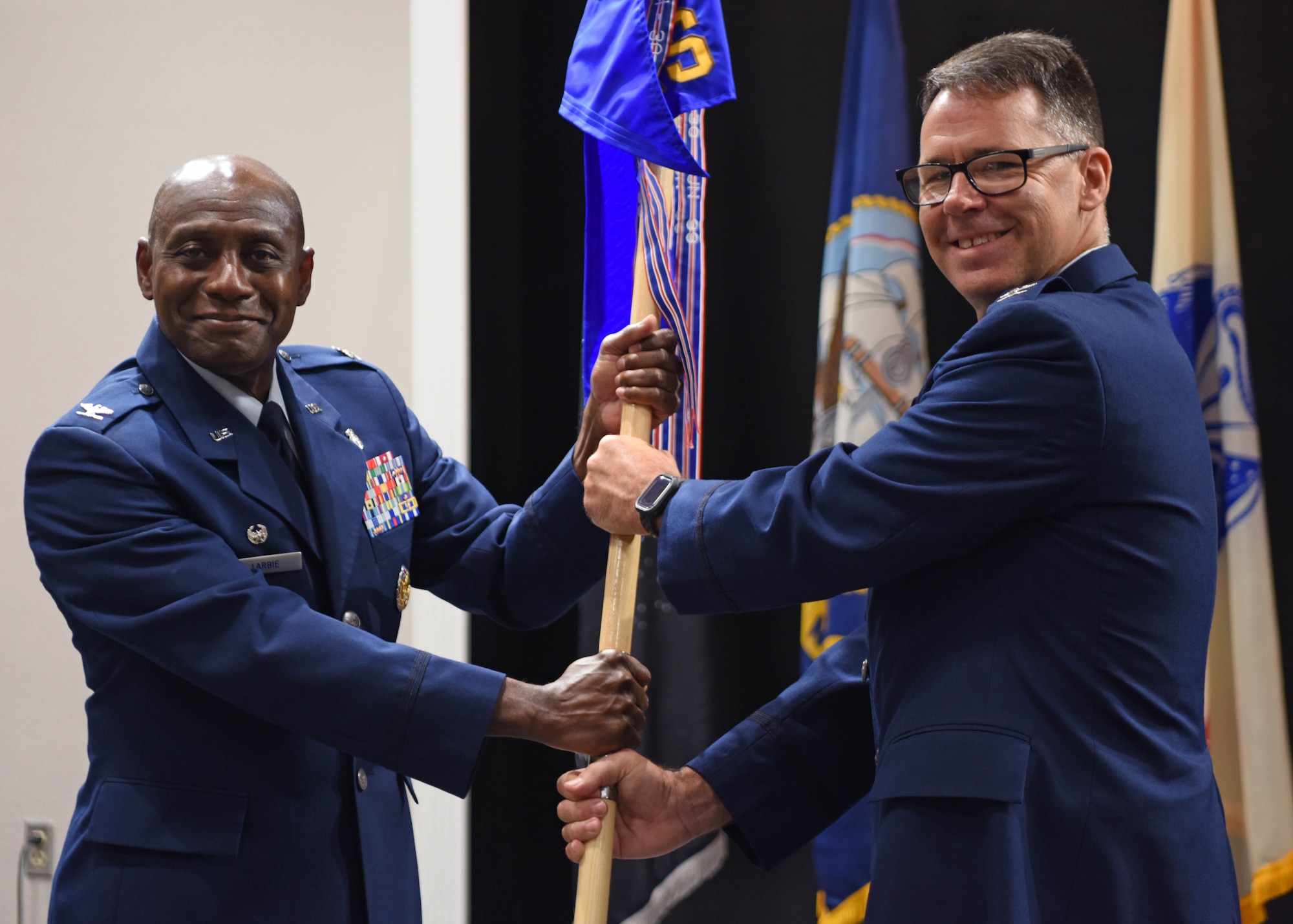 U.S. Air Force Col. Roy Louque, 17th Operational Medical Readiness Squadron outgoing commander, (right) relinquishes command to Col. Derek Larbie, 17th Medical Group commander, during the 17th OMRS change of command ceremony at the Powell Event Center, June 2, 2022. Passing the guidon physically represents the symbolism of passing the squadron responsibilities to the next commander. (U.S. Air Force photo by Senior Airman Ethan Sherwood)