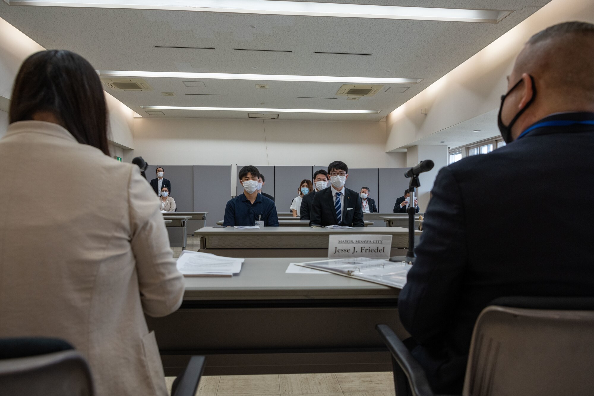 A military member and a translator sit in a room receiving questions.