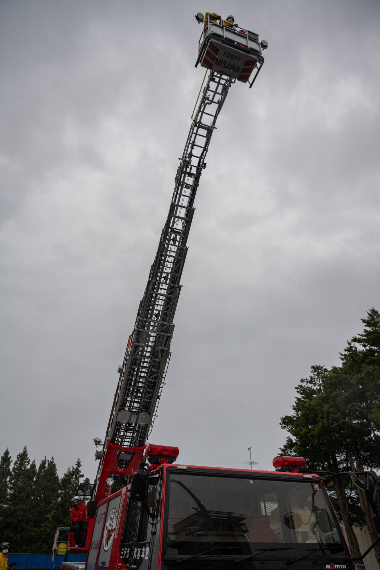 A fire ladder is raised with people on it.