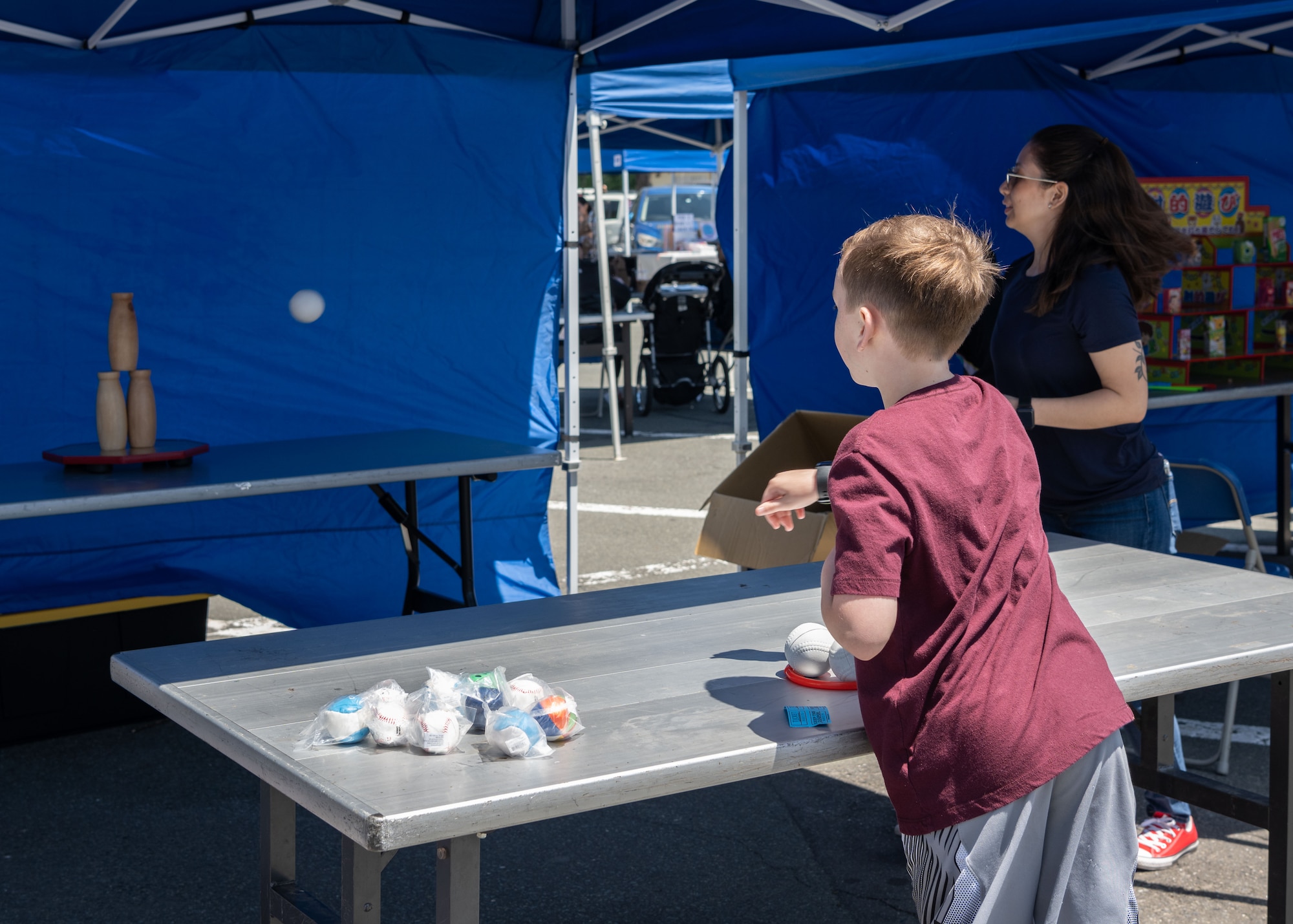 A child throws a softball at milk bottles during a game.