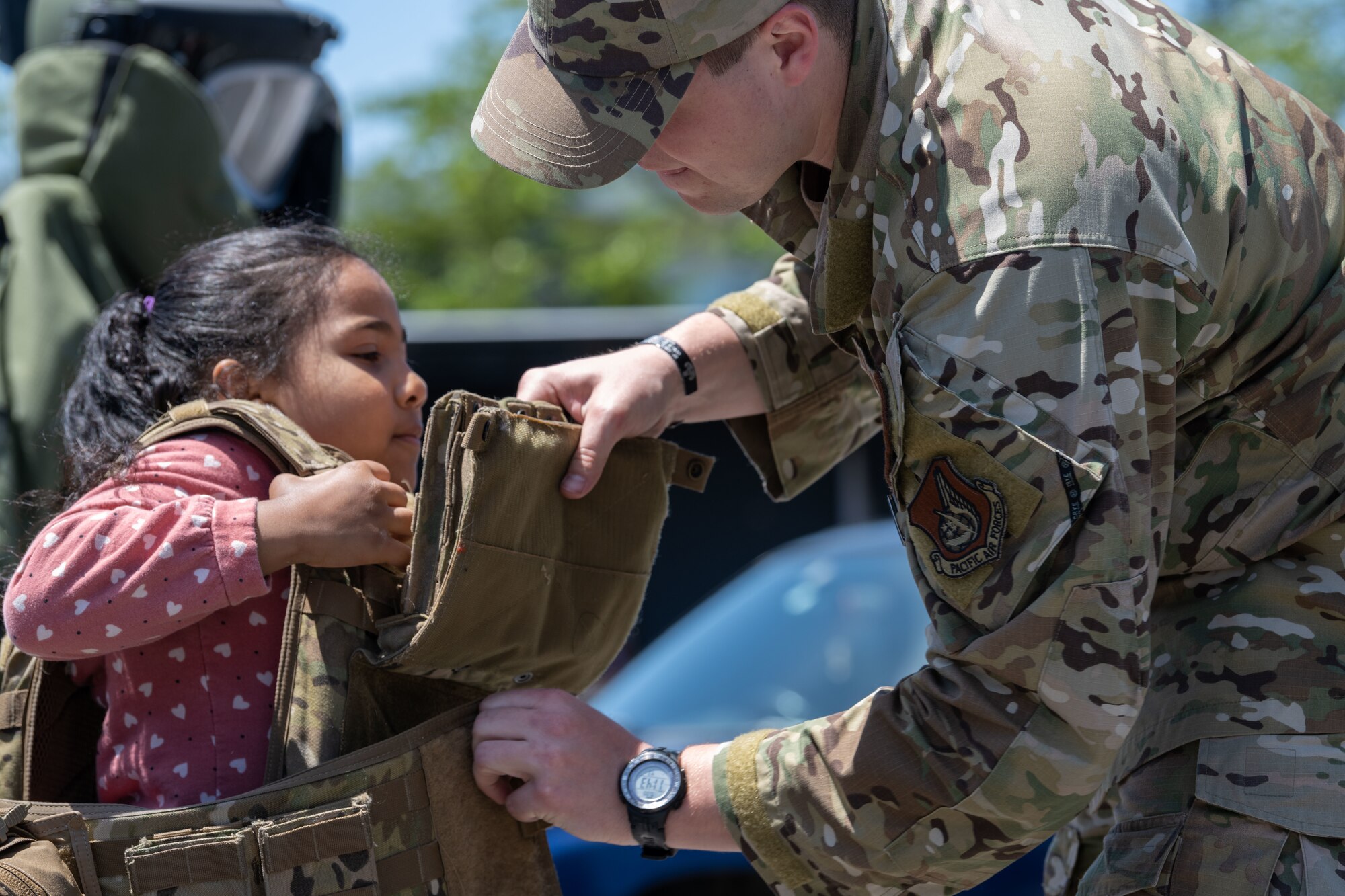A military member helps a child put on military body armor.