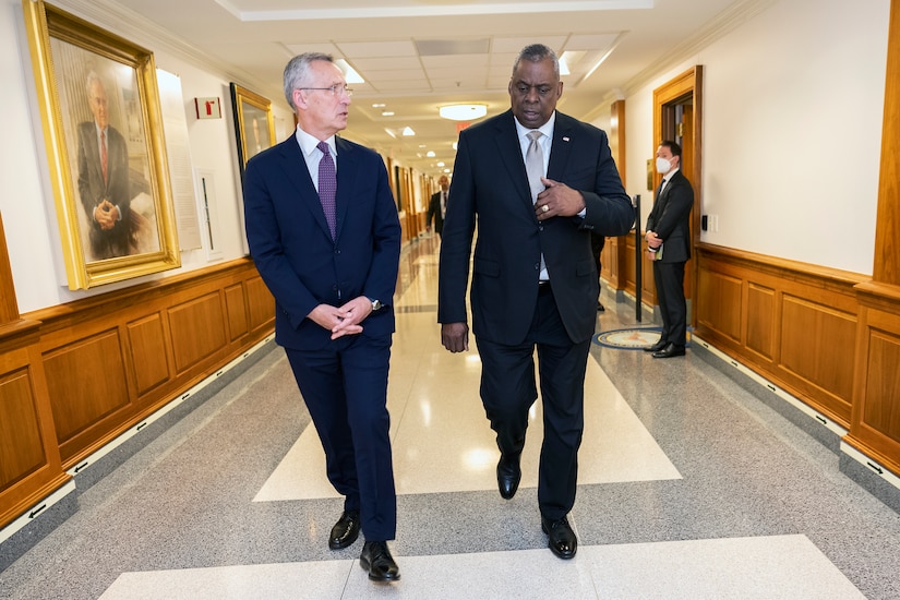 Two men walk down a hallway.