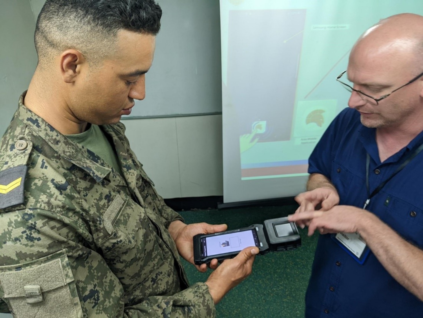 Biometric operations specialist Robert Shelton, right, assigned to Naval Criminal Investigative Service, Technical Services Field Office - Identity Activities branch, Headquarters Quantico, Virginia, demonstrates biometrical enrollments to Tunisian Navy Staff Sergeant Mourad Bel Haj while explaining how to use a fingerprint capture device to take biometric information during exercise Phoenix Express 2022 in Bizerte, Tunisia, May 24, 2022. Phoenix Express 22, conducted by U.S. Naval Forces Africa, is a maritime exercise designed to improve cooperation among participating nations in order to increase maritime safety and security in the Mediterranean.