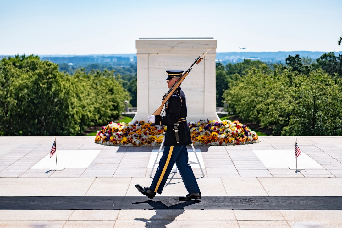 A soldier walks in front of a large memorial.
