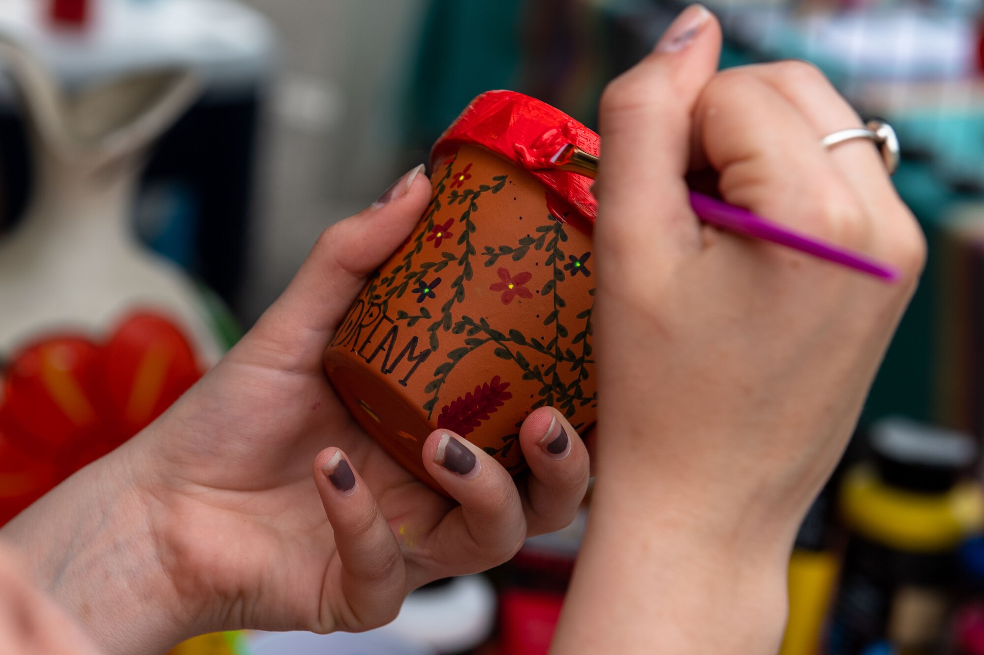 An attendee paints a flower pot at the cultural fair held during Diversity, Equity, Inclusion and Accessibility Day