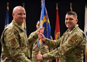 U.S. Air Force Lt. Col. Kara Taylor, 17th Comptroller Squadron outgoing commander, (right) relinquishes command to Col. Matthew Reilman, 17th Training Wing commander, during the 17th CPTS change of command ceremony at the Powell Event Center, June 3, 2022. Passing the guidon physically represents the symbolism of passing the squadron responsibilities to the next commander. (U.S. Air Force photo by Airman 1st Class Sarah Williams)
