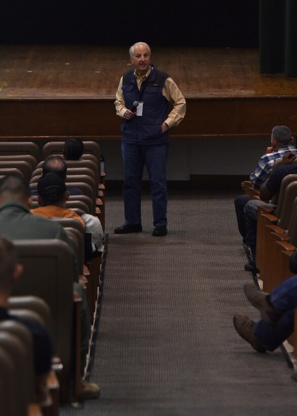 Dr. Ray Ochs stands in front of an audience speaking with a microphone.