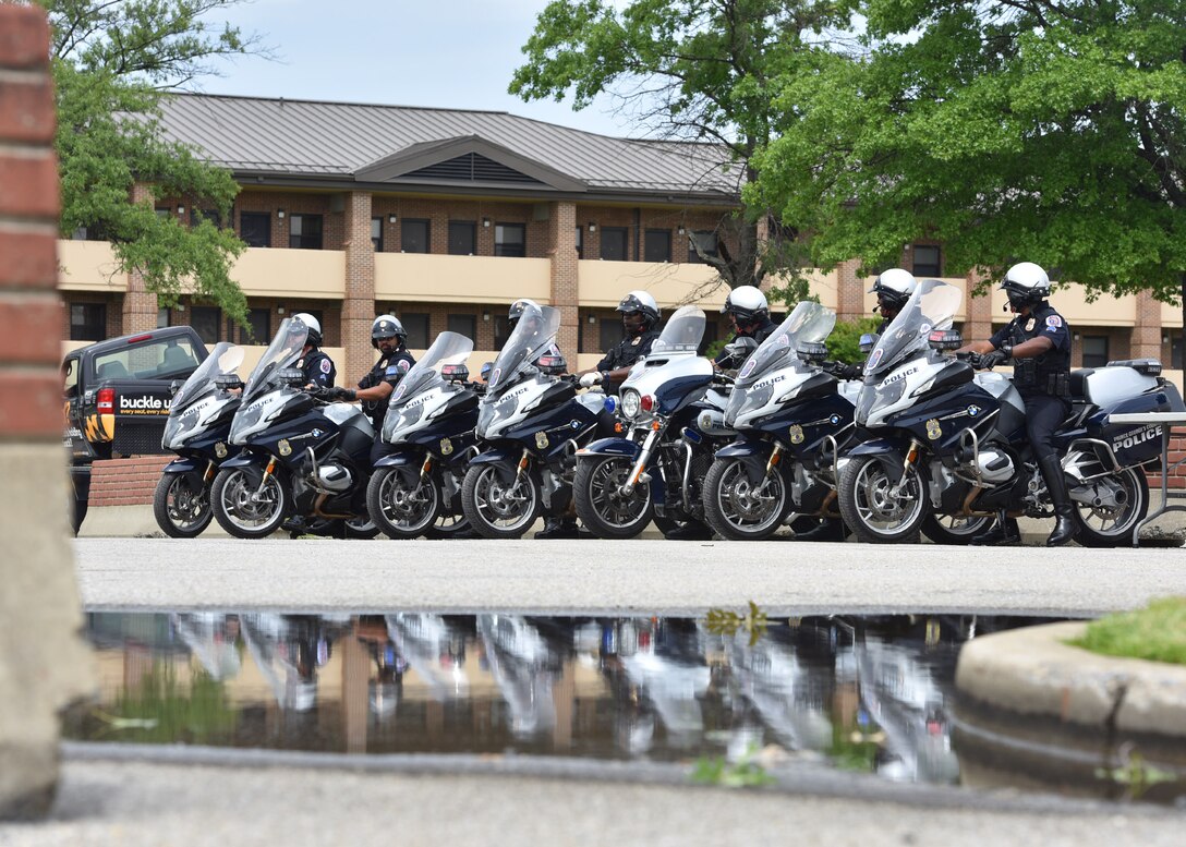 Deputies line up side by side together on their motorcycles and are reflected by the water on the ground.