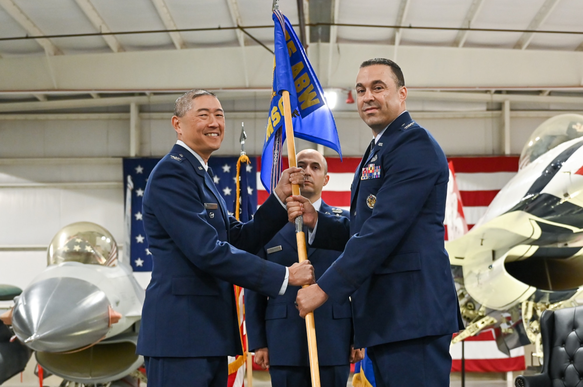 Right, Col. Khalim A. Taha, incoming 75th Mission Group commander, receives the guidon from Col. Peter Feng, 75th Air Base Wing vice commander