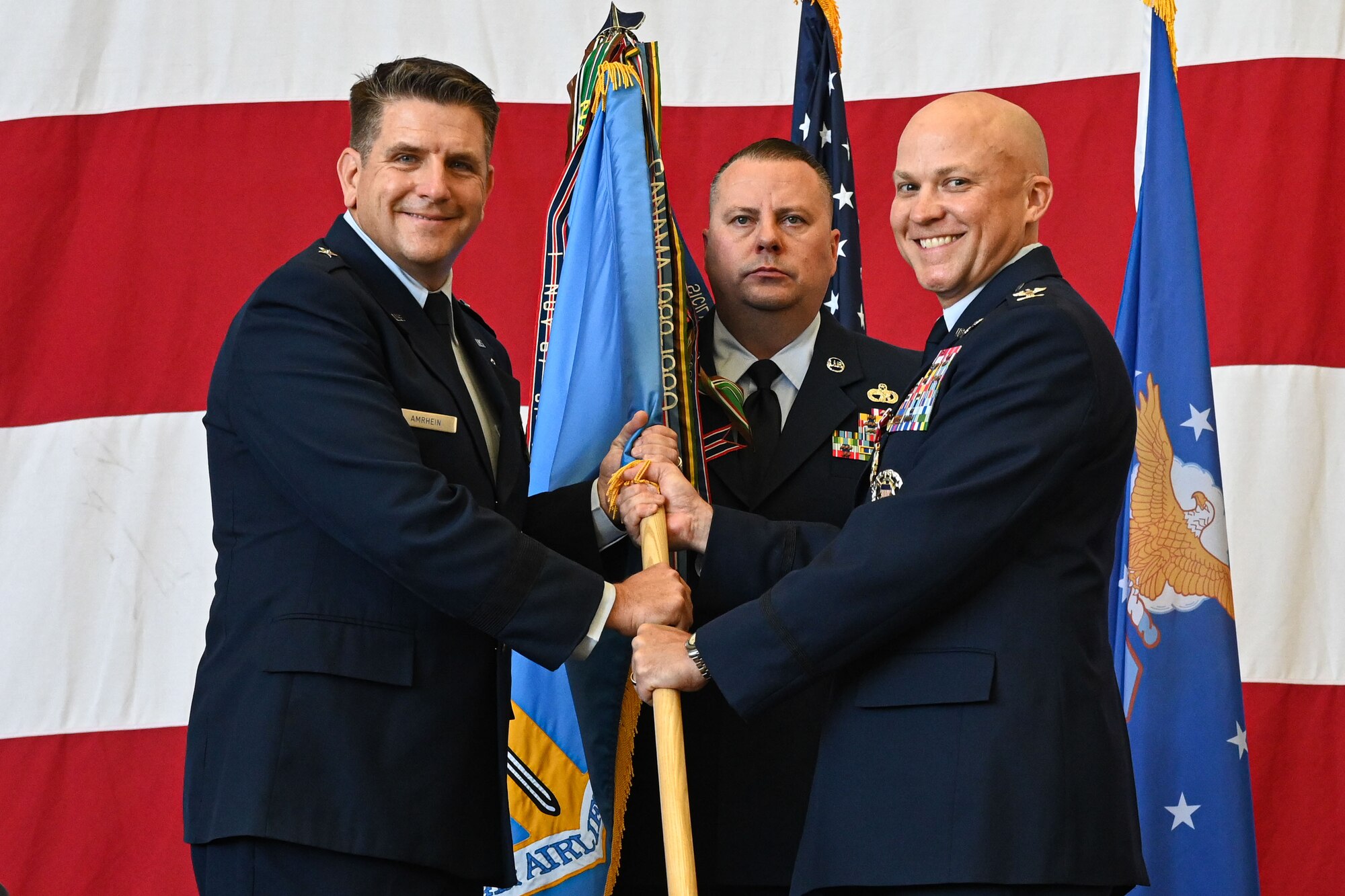 Brig. Gen. Christopher Amrhein, 19th Air Force vice commander, left, retrieves the wing guidon from Col. Joseph Miller, former 314th Airlift Wing commander, right, as he relinquishes command of the wing