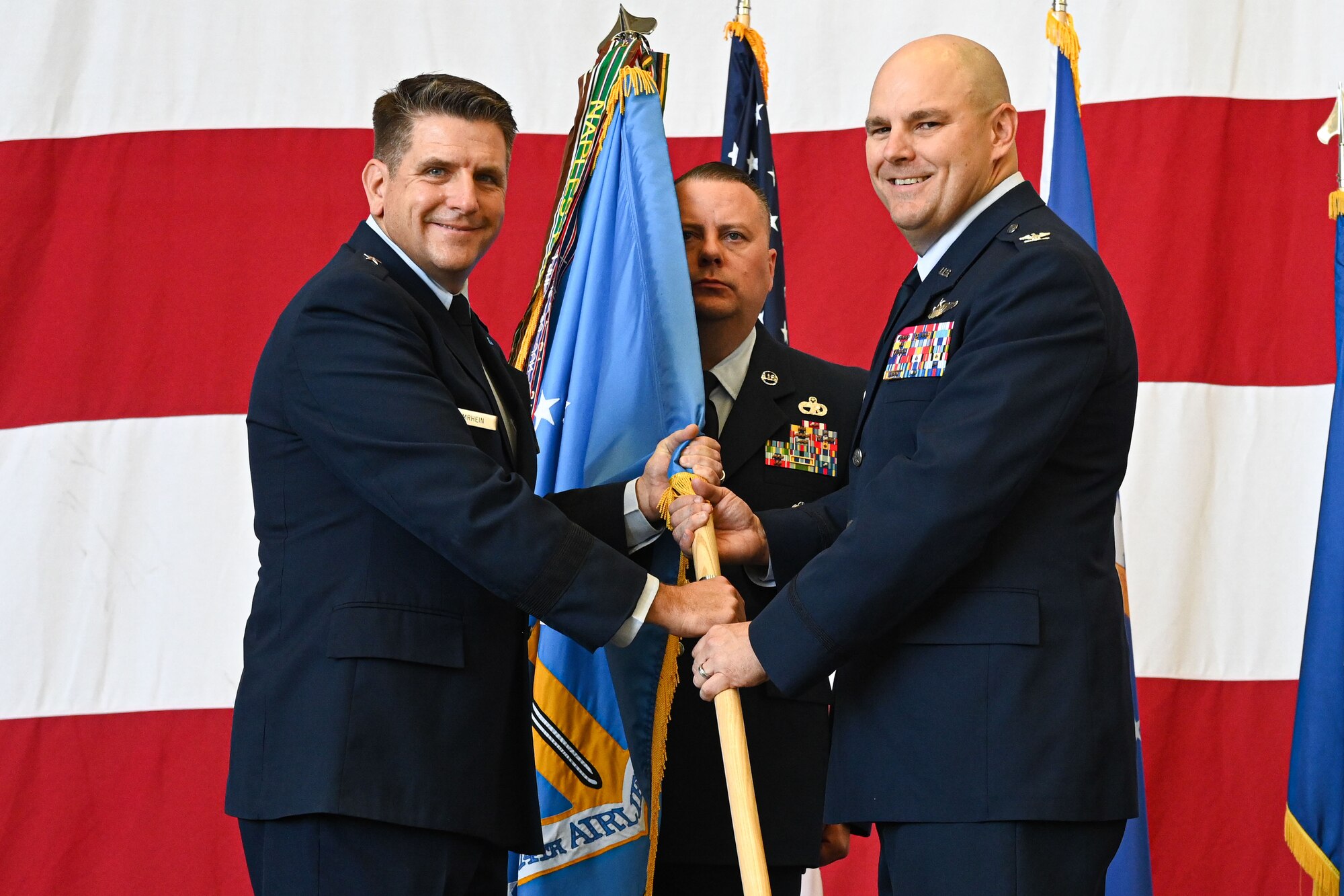 Brig. Gen. Christopher Amrhein, 19th Air Force vice commander, left, passes the wing guidon to Col. Jonathan Tucker, 314th Airlift Wing commander, right, as he assumes command of the wing