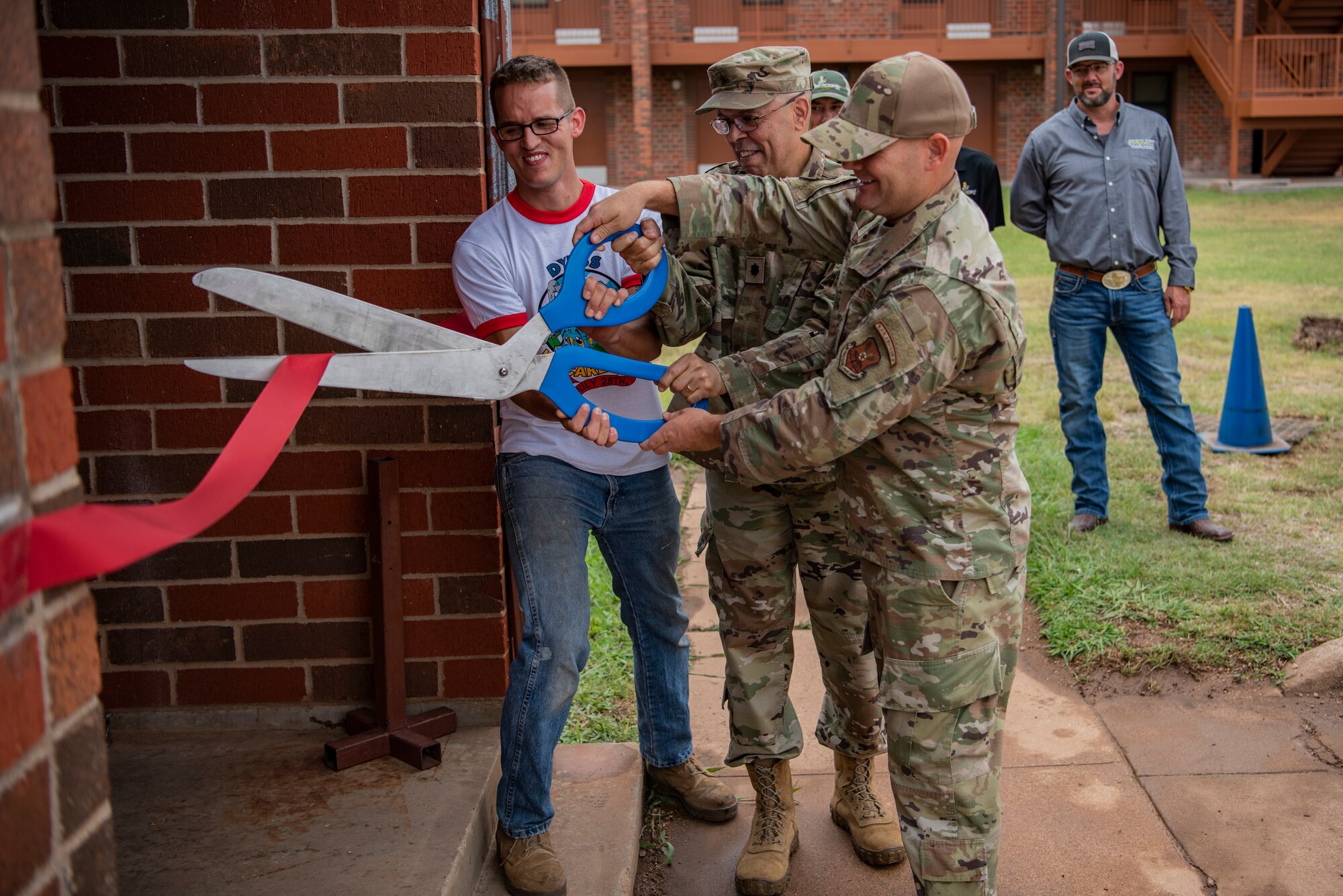 Senior Airman Dustin Brooks, Dyess We Care Team leader and logistics manager, Chaplain (Lt. Col) Gabriel Rios, 7th Bomb Wing wing chaplain, and Chief Master Sgt. Matthew Coltrin, 7th BW command chief, cut a ribbon during the grand re-opening of the Soul Fire Café at Dyess Air Force Base, Texas, June 3, 2022. Soul Fire Café provides Airmen a venue to unwind and relax. (U.S. Air Force photo by Airman 1st Class Ryan Hayman)