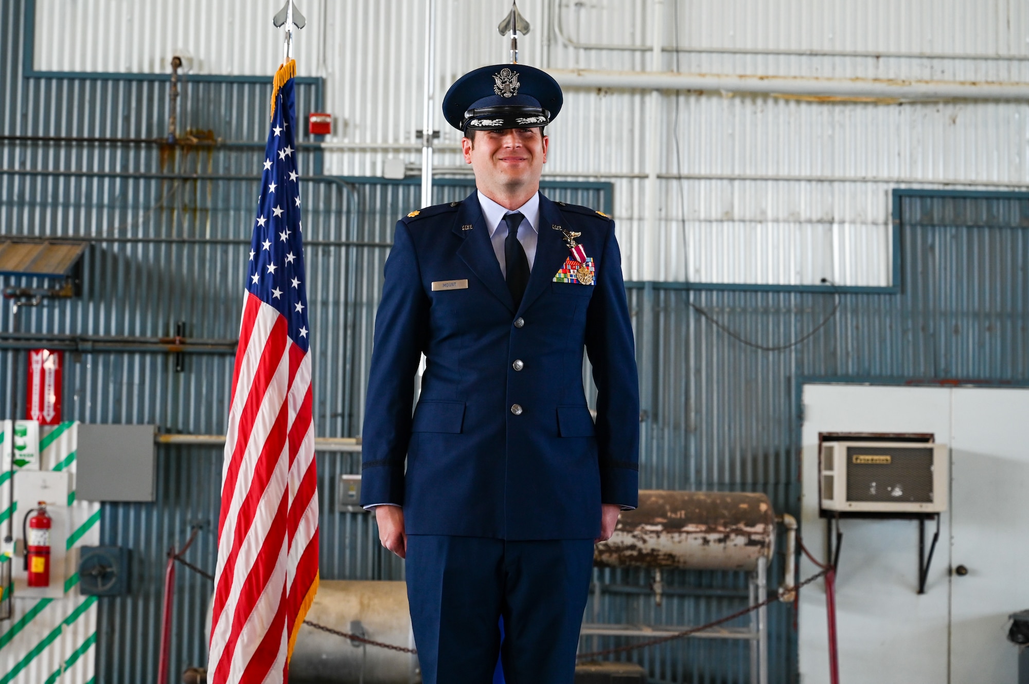 Airman standing in front of flag.