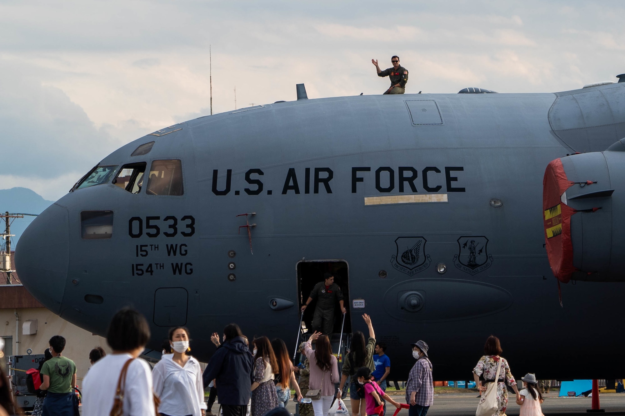 Capt. Logan Hawke, 535th Airlift Squadron pilot, waves to festival visitors from the top of a C-17 Globemaster III at the Friendship Festival 2022 at Yokota Air Base, Japan, May 22, 2022. The festival was an opportunity for visitors to learn and celebrate the partnership between the U.S. and Japan, while strengthening the bonds between Yokota and the local communities. (U.S. Air Force photo by Airman 1st Class Makensie Cooper)