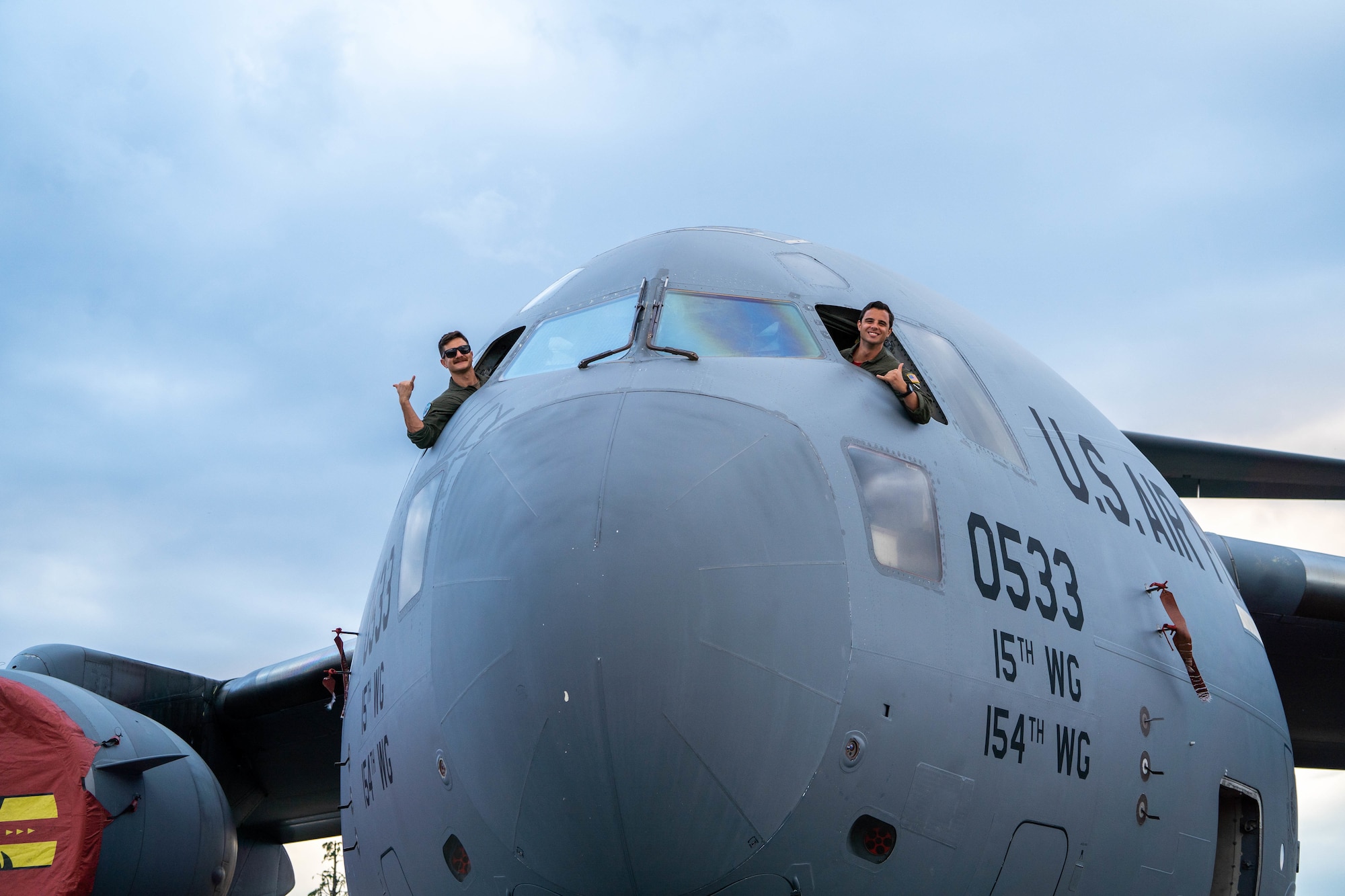 Senior Airman Jordan Brown, 535th Airlift Squadron loadmaster and Capt. Logan Hawke, 535th AS pilot looks out the window of the C-17 Globemaster III cockpit during the Friendship Festival 2022 at Yokota Air Base, Japan, May 22, 2022. The festival embodied the true spirit of friendship, welcoming more than 110,000 Japanese neighbors to meet with our Airmen and tour static displays of U.S and Japanese Aircraft while sharing our cultures and stories. (U.S. Air Force photo by Airman 1st Class Makensie Cooper)