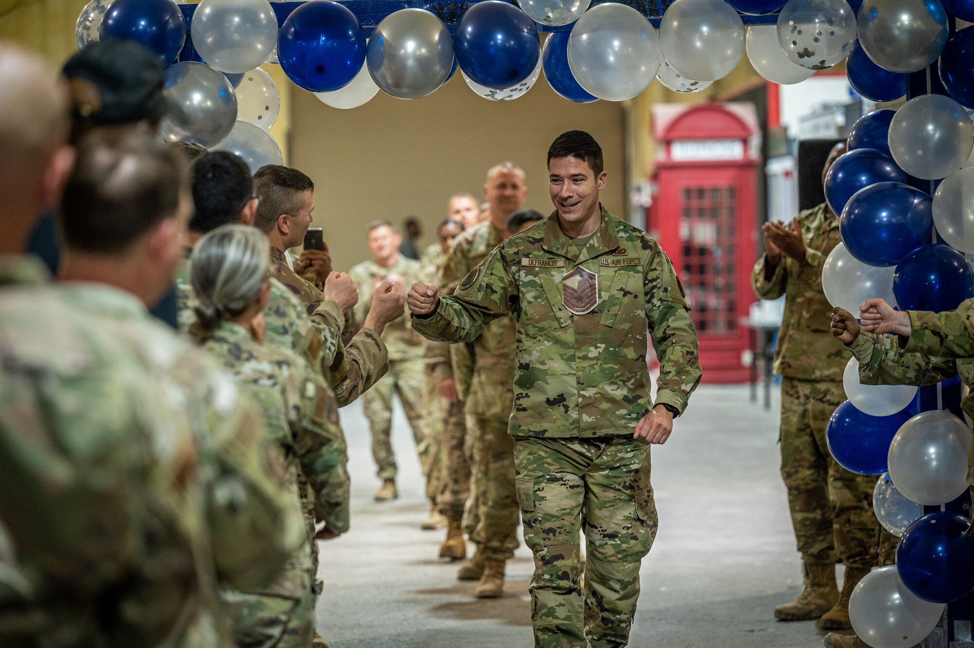 Technical Sgt. Kyle DeFrancis, U.S. Embassy Defense Attaché Office, walks toward the stage receiving congratulatory fist bumps from fellow Red Tails at the 332d Air Expeditionary Wing master sergeant release party June 1, 2022, at an undisclosed location in Southwest Asia. This year, the active duty Air Force selected 4,040 of 27,296 eligible technical sergeants for the promotion to master sergeant, at a selection rate of 14.8%.  (U.S. Air Force photo by Master Sgt. Christopher Parr)