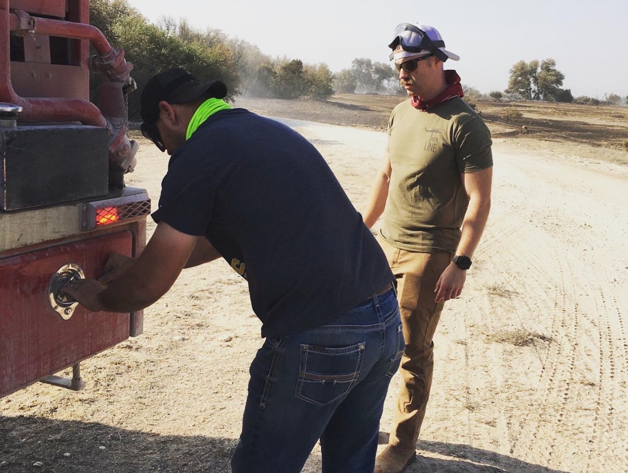 One man operates outside an emergency vehicle, while another observes.