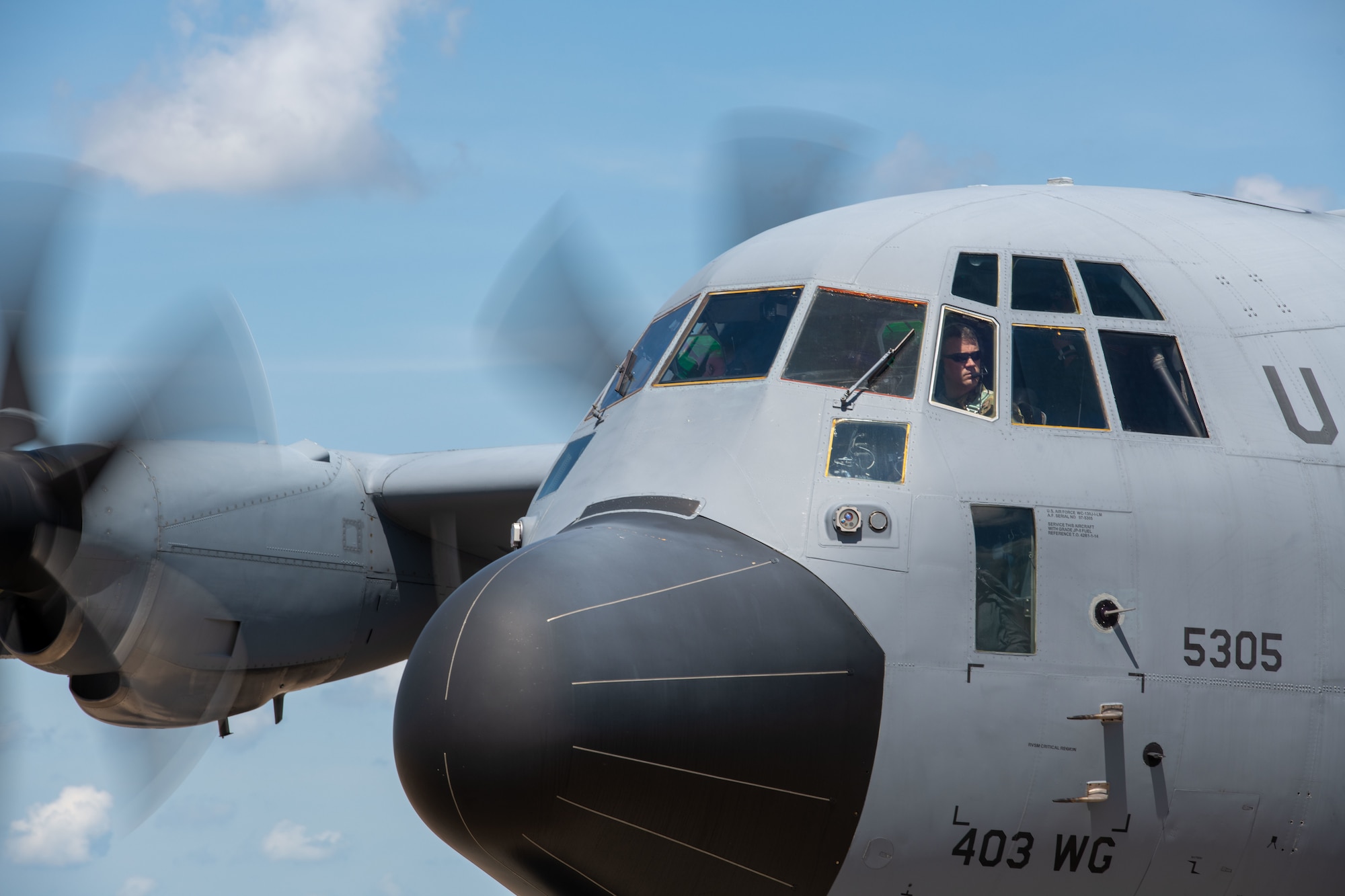 A pilot looks out of the window of a WC-130J.