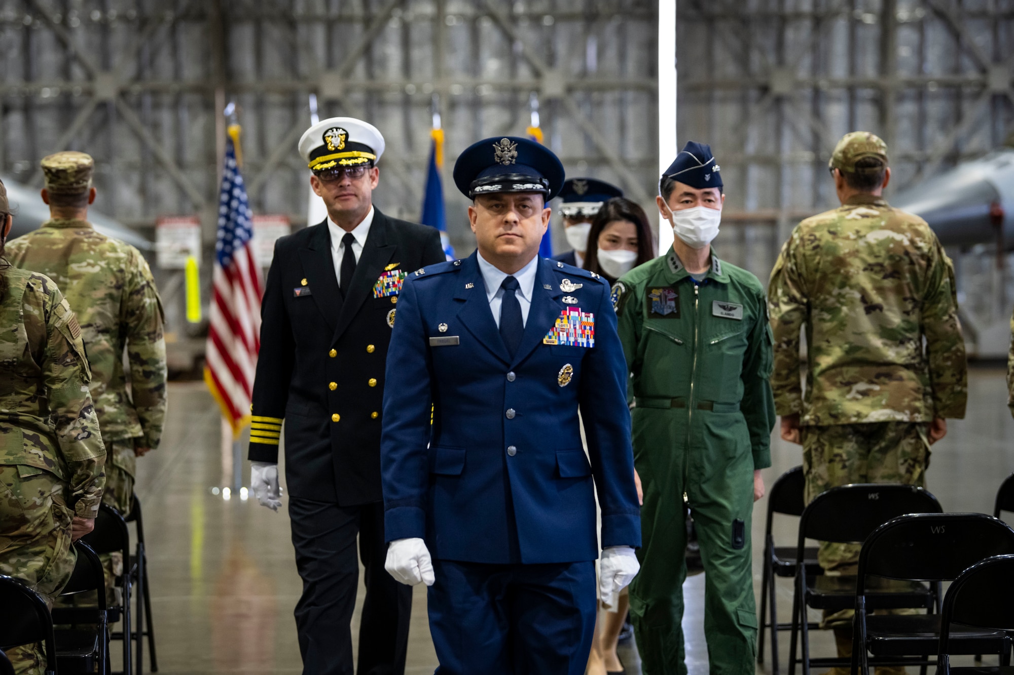 Military members in uniform walk away from ceremony.