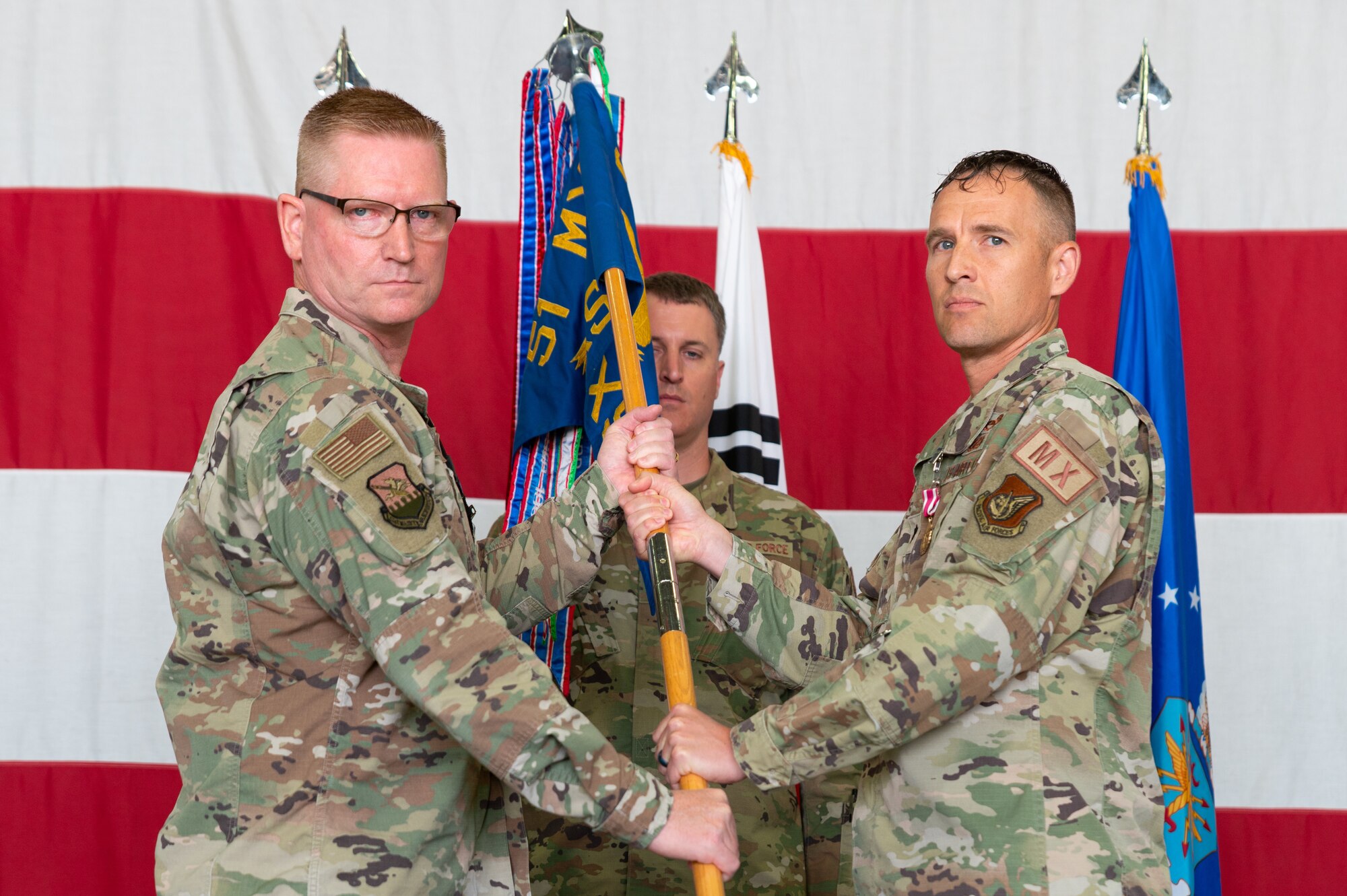 Col. Brian D. Moore, 51st Maintenance Group commander, left, recives the 51st Aircraft Maintnance Squadron guidon from Lt. Col. Jared C. Struck, outgoing 51st AMXS commander, right