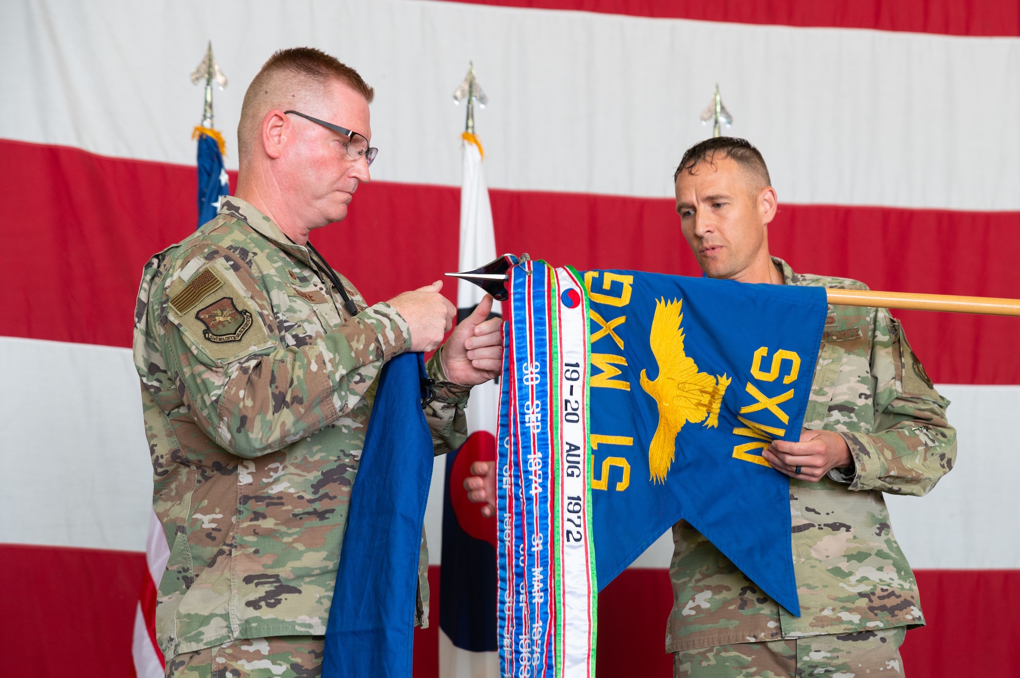Col. Brian D. Moore, 51st Maintenance Group commander, left, assists Lt. Col. Jared C. Struck, outgoing 51st Aircraft Maintenance Squadron commander, right