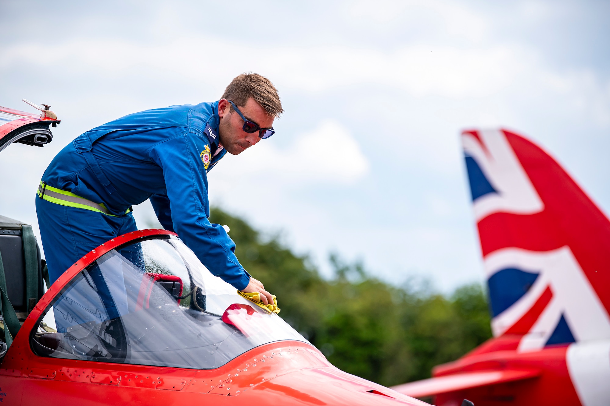Royal Air Force Corporal James Hiles, Red Arrows engineering technician, wipes the mirror of a Hawk T1 aircraft at RAF Fairford, England, June 2, 2022. The Red Arrows landed at Fairford to refuel in preparation for the Queen’s Platinum Jubilee Ceremonies and Midlands Air Festival. (U.S. Air Force photo by Staff Sgt. Eugene Oliver)