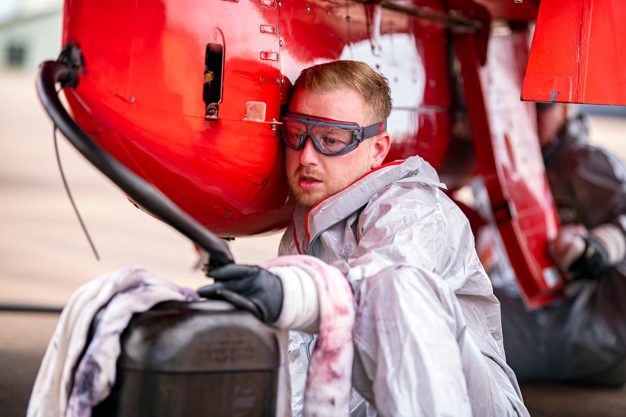 A Royal Air Force Red Arrows dye team member refuels the dye canisters on a Hawk T1 aircraft at RAF Fairford, England, June 2, 2022. The Red Arrows landed at Fairford to refuel in preparation for the Queen’s Platinum Jubilee Ceremonies and Midlands Air Festival. (U.S. Air Force photo by Staff Sgt. Eugene Oliver)