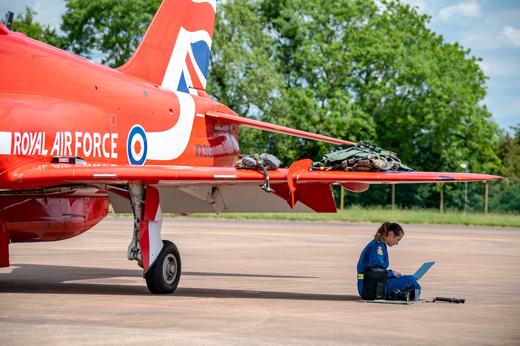 A member of the Royal Air Force aerobatic team, known as the Red Arrows, works on a laptop at RAF Fairford, England, June 2, 2022. The Red Arrows landed at Fairford to refuel in preparation for the Queen’s Platinum Jubilee Ceremonies and Midlands Air Festival. (U.S. Air Force photo by Staff Sgt. Eugene Oliver)