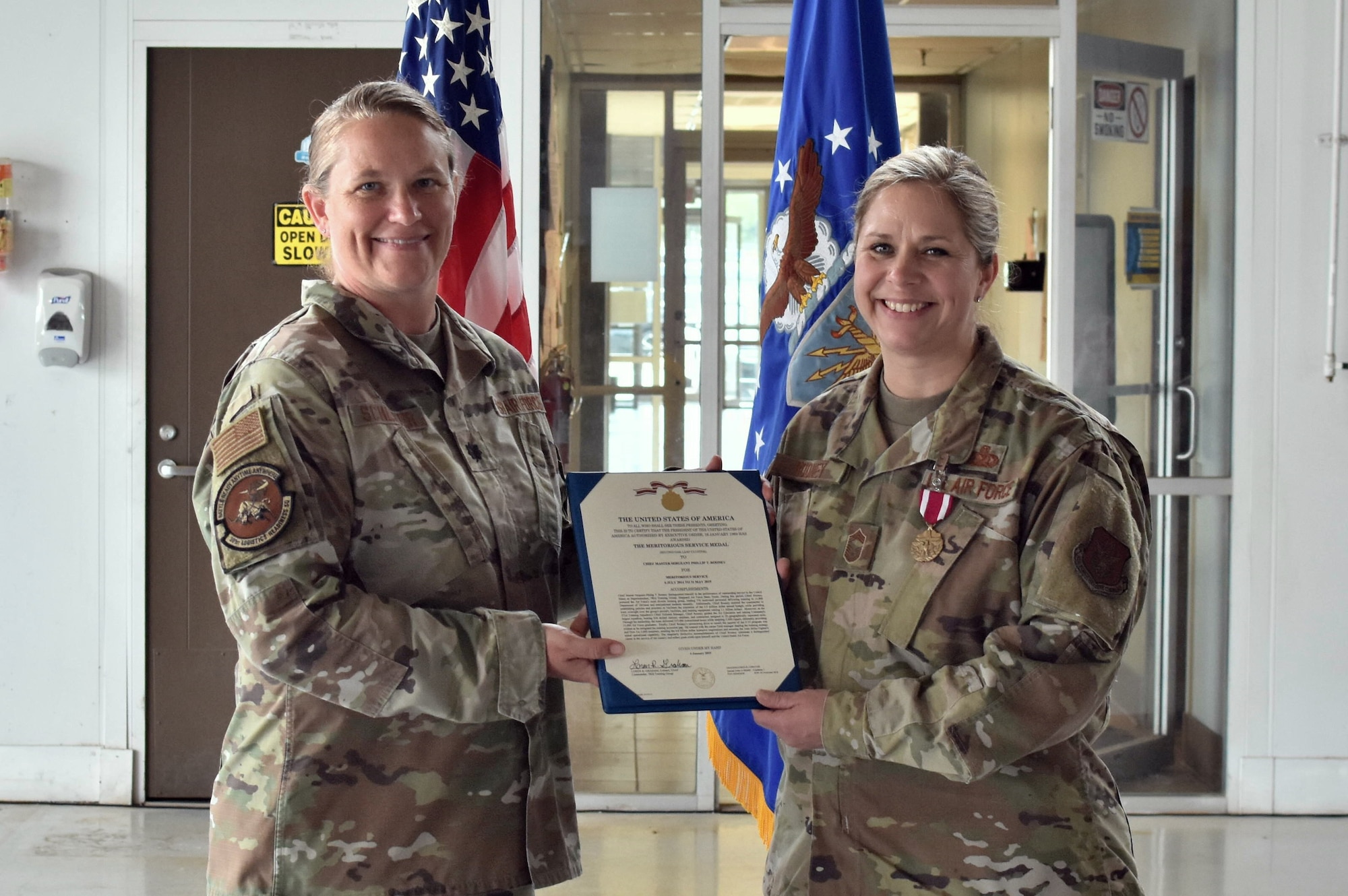 Lt. Col. Farrah Schluter, 301st Logistics Readiness Squadron commander, and Chief Master Sgt. Angela Rooney, 301 FW LRS senior enlisted leader, hold Rooney’s retirement order at Naval Air Station Joint Reserve Base Fort Worth, Texas on June 4, 2022. Rooney officially retires in October 2022, after 25 years of military service. (U.S. Air Force photo by Staff Sgt. Randall Moose)