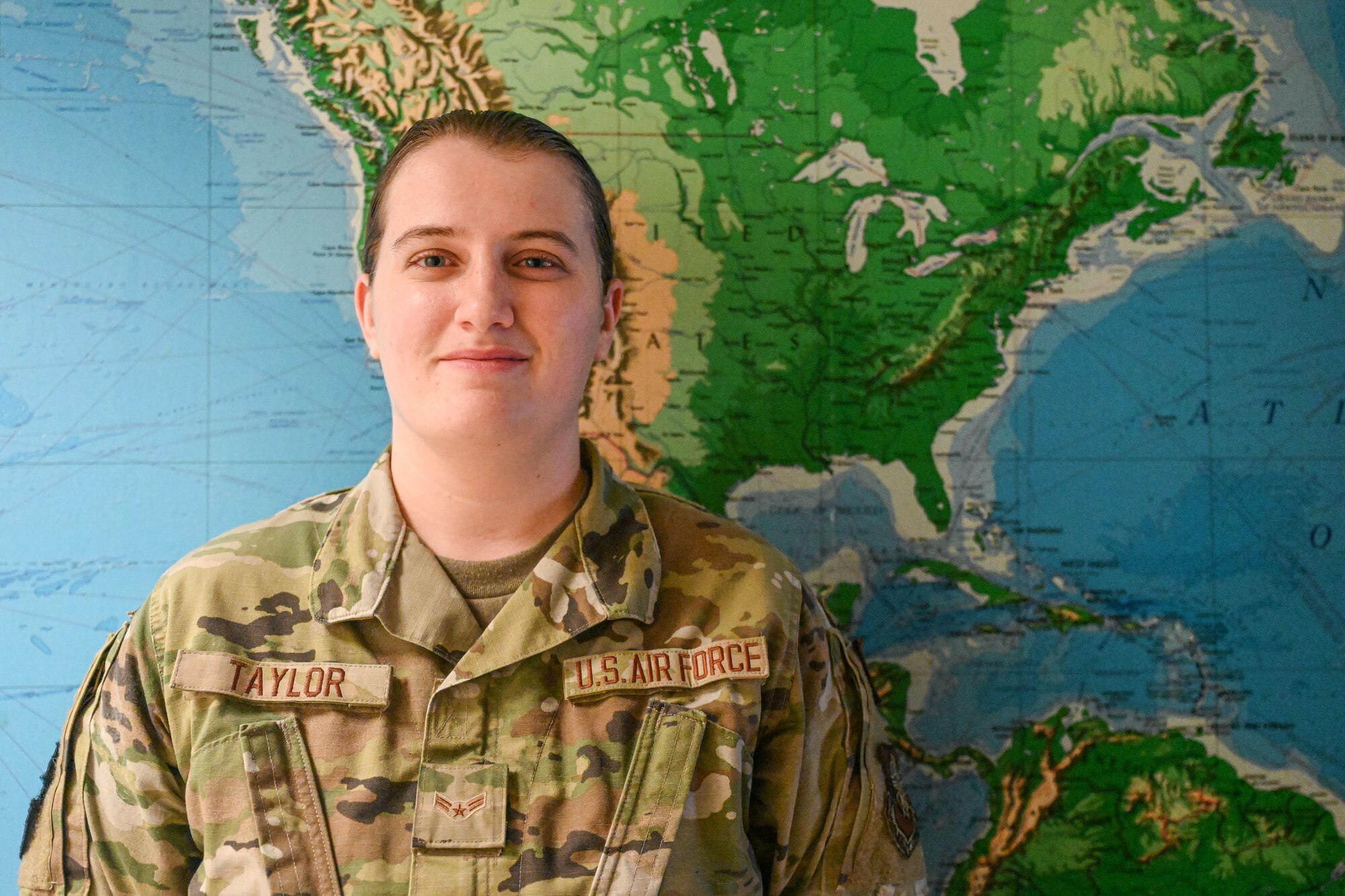 An Airman stands in front of a map.