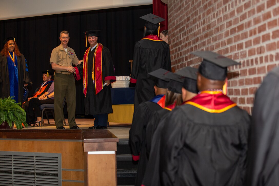 U.S. Marine Corps Col. Mikel Huber, commanding officer of Marine Corps Air Station (MCAS) Cherry Point, presents awards to graduates during the 46th Annual Voluntary Education Graduation Ceremony at Two Rivers Theater, MCAS Cherry Point, North Carolina, June 2, 2022. The goals of the voluntary education programs are to provide a broad range of personal and professional learning opportunities to improve the academic abilities of active-duty personnel to assist in their career progression and to generally strengthen the military community. (U.S. Marine Corps photo by Lance Cpl. Symira Bostic)