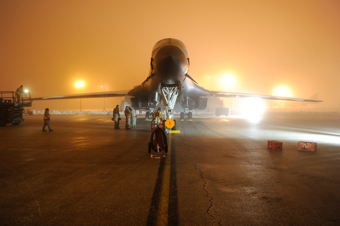 Several service members work around a large aircraft at night.