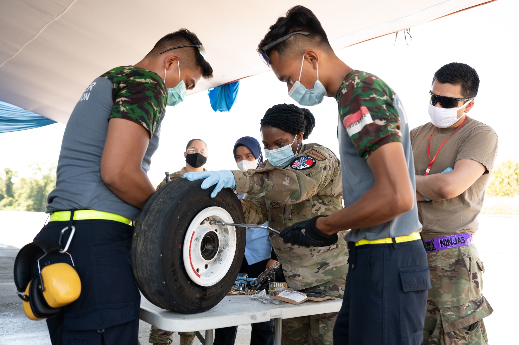 Indonesian Air Force 2nd Sergeants Rajas Febry, and Didit Dwe perform wheel and tire maintenance with U.S. Air Force Staff Sgt. Za'Queta Eddins, 35th Maintenance Group Transient Alert noncommissioned officer in charge, during Cope West 21 at Roesmin Nurjadin Air Force Base in Pekanbaru, Riau, Indonesia. June 23, 2021. U.S. Airmen worked together with the Indonesian Air Force in the air and on the ground to facilitate subject-matter expert exchanges strengthening our interoperability. (U.S. Air Force photo by Staff Sgt. Matthew Kakaris)