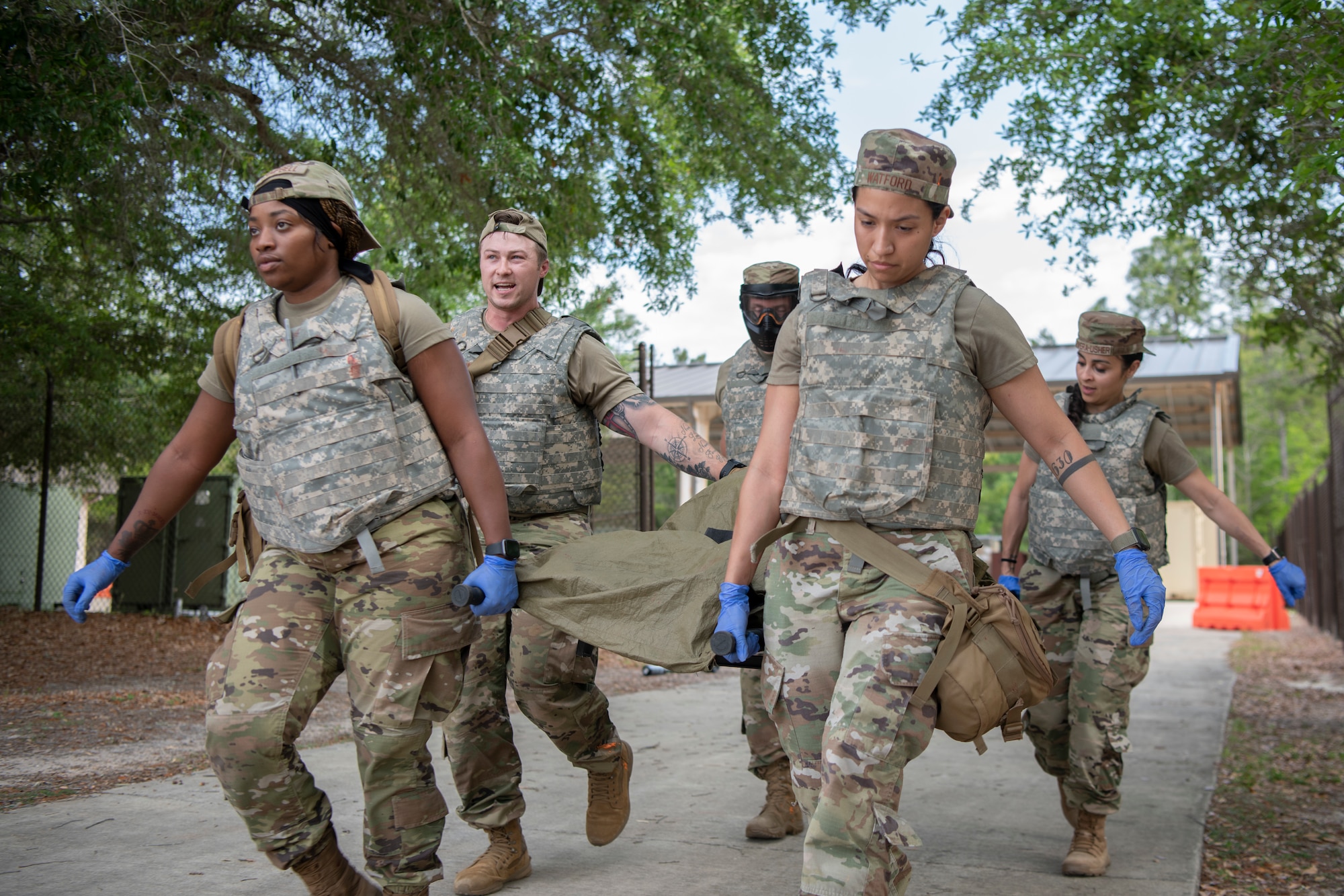 Air Commandos with the 1st Special Operations Healthcare Operations Squadron and the 1st Special Operations Medical Group carry a SIM Manikin to safety using a stretcher during tactical combat casualty care training April 29, 2022, at Hurlburt Field, Florida.