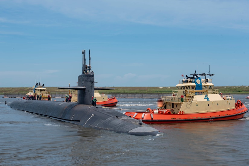 A submarine is pushed into place by tugboats.
