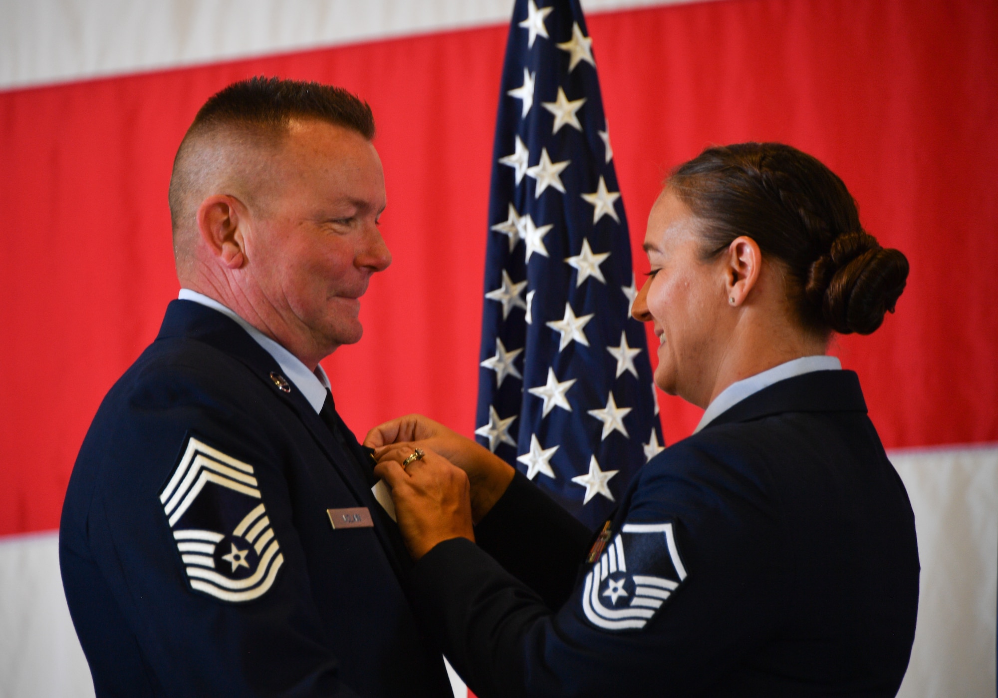 Master Sgt. Renee Mclain affixes Chief Master Sgt. James Mclain’s retirement pin to his collar during his retirement ceremony at Naval Air Station Joint Reserve Base Fort Worth, Texas, June 4, 2022. Mclain  held numerous positions of responsibility at the 301st Fighter Wing since 2007 and ended his career as the 301st Maintenance Squadron superintendent.(U.S. Air Force photo by Staff Sgt. Nije Hightower)