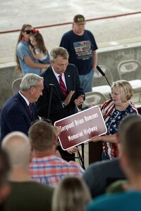 Melinda Clary, Sgt. Brian Romines’ mother, along with State Rep. Patrick Windhorst and State Sen. Dale Fowler, unveil the highway sign designating Illinois Highway 146 from Anna to Vienna, Illinois, as the Sergeant Brian Romines Memorial Highway during the dedication ceremony June 6 in Anna, Illinois.