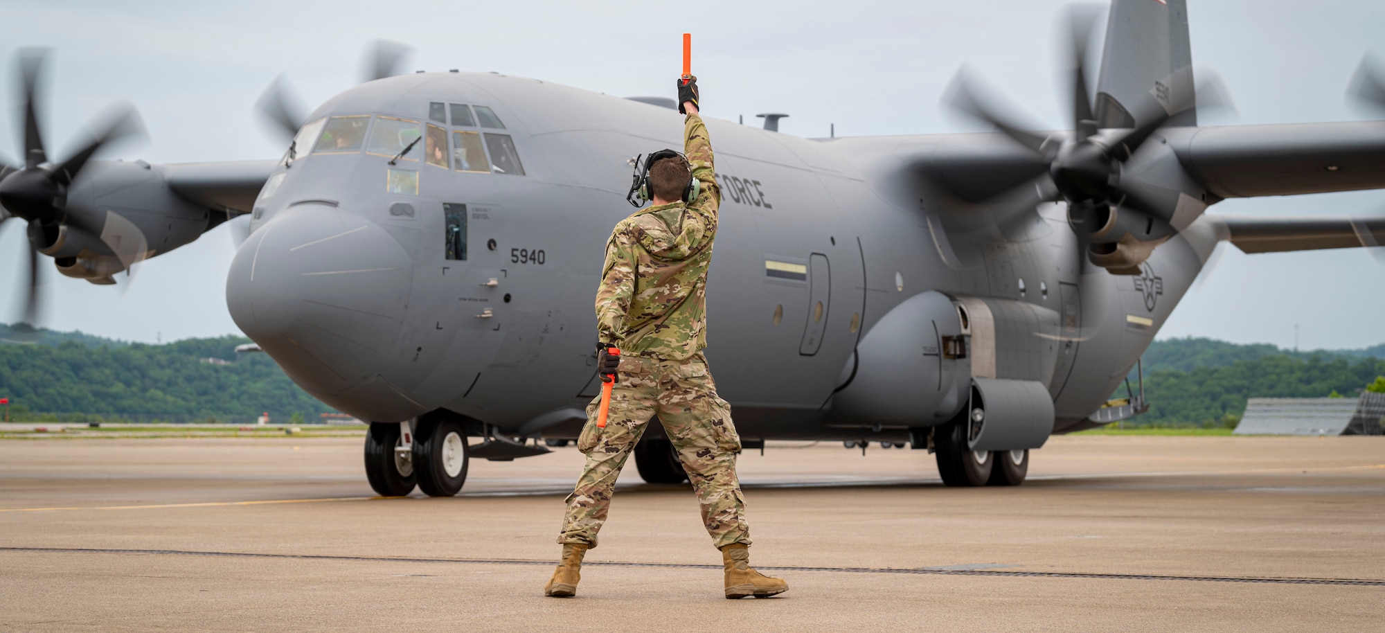 A C-130 J-30 Super Hercules parks at McLaughlin Air National Guard Base, as an airman directs the pilot.