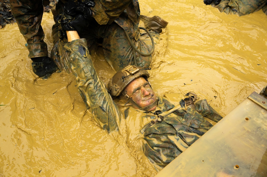 A Marines lays in mud during a competition.