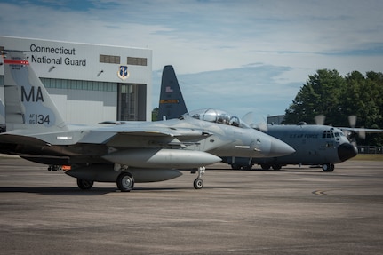 Military aircraft sit near each other at an airport.