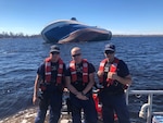 Coast Guard Fort Lauderdale 45-foot Response Boat-Medium crewmembers stand in front of a capsized boat at St. Andrews Bay, Florida, Oct. 22, 2018. The boatcrew spotted the capsized boat during a law enforcement patrol through a Hurricane Michael high-impact area. Coast Guard Photo by Petty Officer 3rd Class David Brindley.