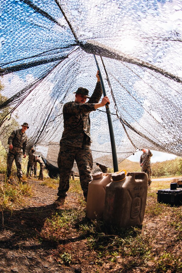 A U.S. Marine with 3d Marine Littoral Regiment, 3d Marine Division, sets up camouflage netting at Marine Corps Training Area Bellows, Hawaii, May 30, 2022. U.S. Marines with 3d MLR conducted the training in order to enhance unit cohesion and combat readiness. (U.S. Marine Corps photo by Cpl. Patrick King)