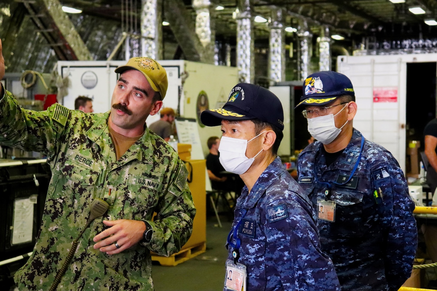 SASEBO, Japan (June 1, 2022) Ensign David Pierce, from Pittsburgh, explains to Japan Maritime Self-Defense Force Vice Adm. FUKUDA Tatsuya, commander, Fleet Escort Force, and Rear Adm. SHIMIZU Hitoshi, commander, Escort Flotilla Two, how the twin-boom extensible crane (TBEC) is utilized to launch an 11m rigid-hulled inflatable boat (RHIB) out of the stern on the Independence-class littoral combat ship USS Charleston (LCS 18). Charleston, part of Destroyer Squadron (DESRON) 7, is on a rotational deployment, operating in the U.S. 7th Fleet area of operations to enhance interoperability with partners and serve as a ready-response force in support of a free and open Indo-Pacific region. (U.S. Navy photo by Lt. j.g. James French)