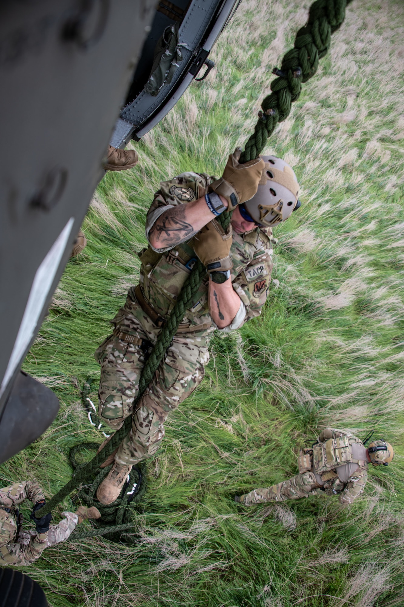 uniformed military members slide down rope