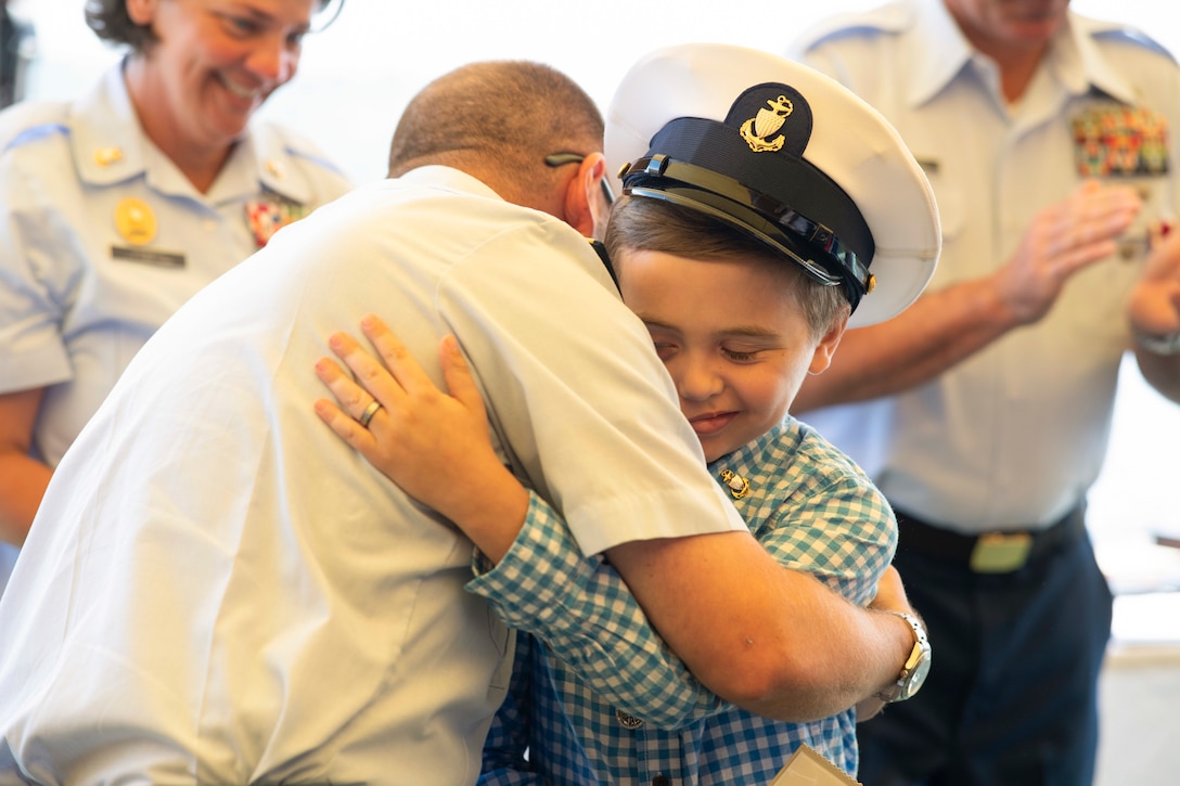 A son hugs his father during a ceremony.