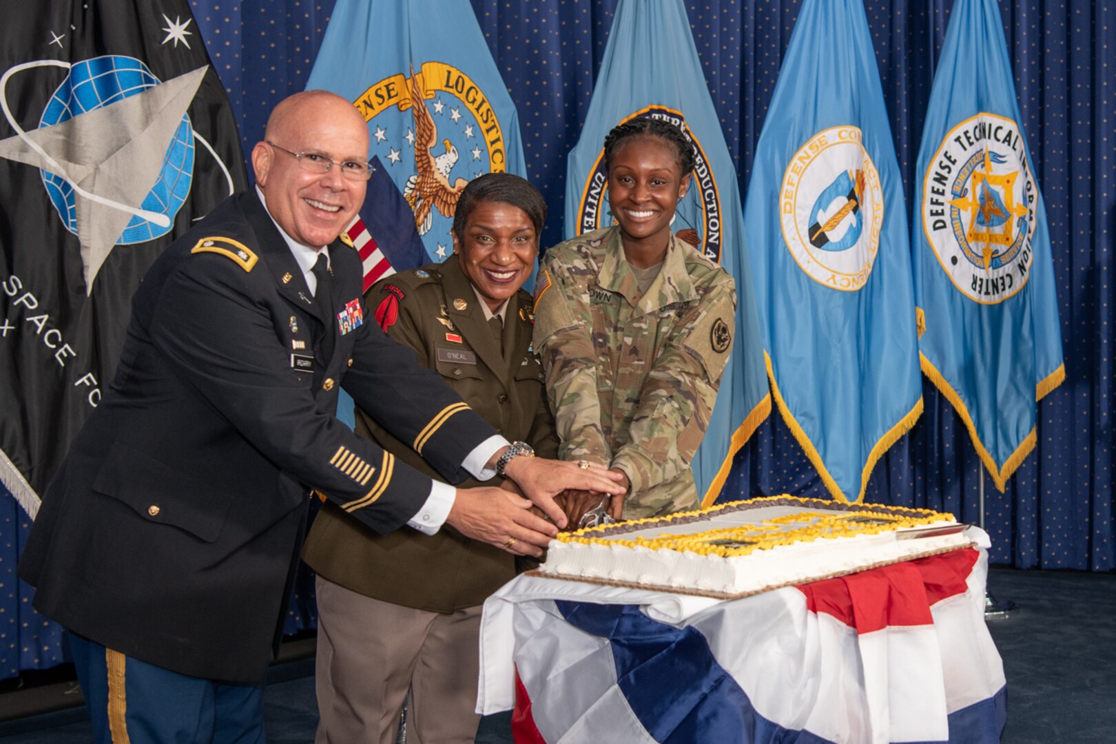 The oldest and youngest soldiers--Army Lt. Col. Alan M. Irizarry, Joint Base Myer-Henderson Hall garrison chaplain, and Army Sgt. Capri A. Brown from DLA Protocol with Army Command Sgt. Maj. Tomeka O’Neal, Defense Logistics Agency senior enlisted leader (center)– cut the Army birthday cake June 7 in the McNamara Headquarters Complex, Fort Belvoir, Virginia. Photo by Christopher Lynch