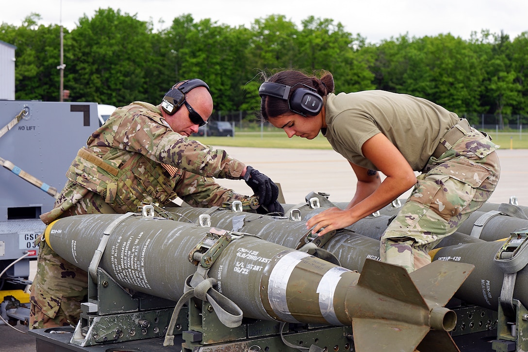Two airmen secure simulated bombs during training.